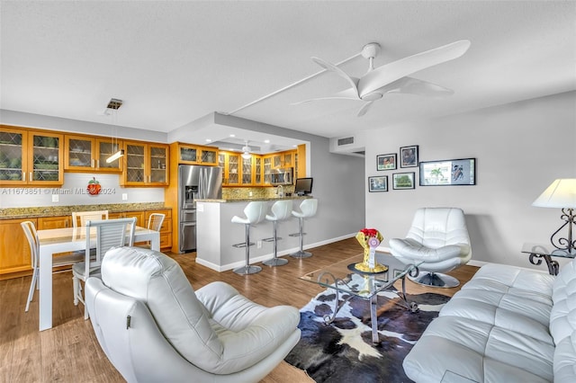 living room with hardwood / wood-style flooring, ceiling fan, and a textured ceiling