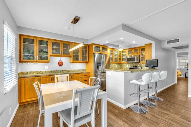 kitchen featuring wood-type flooring, light stone countertops, a wealth of natural light, and stainless steel appliances