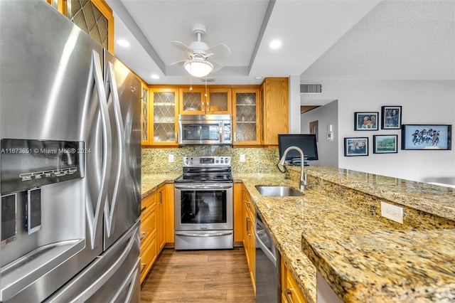 kitchen with decorative backsplash, sink, stainless steel appliances, light stone countertops, and dark hardwood / wood-style floors