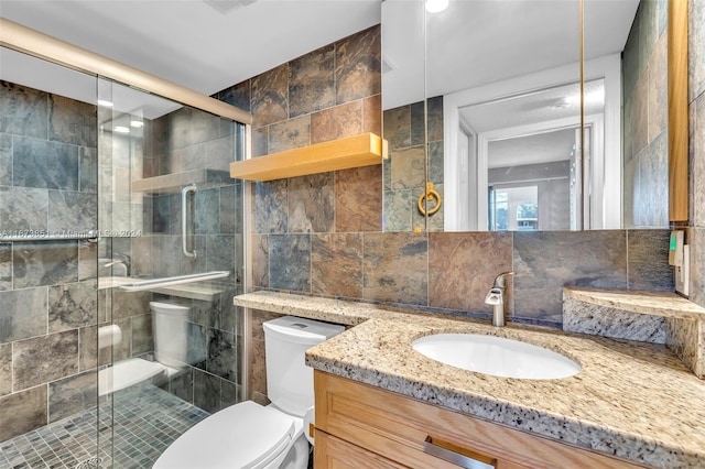 bathroom featuring tile walls, a shower with shower door, vanity, and toilet