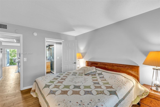 bedroom featuring light wood-type flooring and connected bathroom