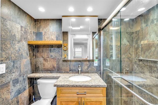 bathroom with an enclosed shower, toilet, vanity, and tile walls