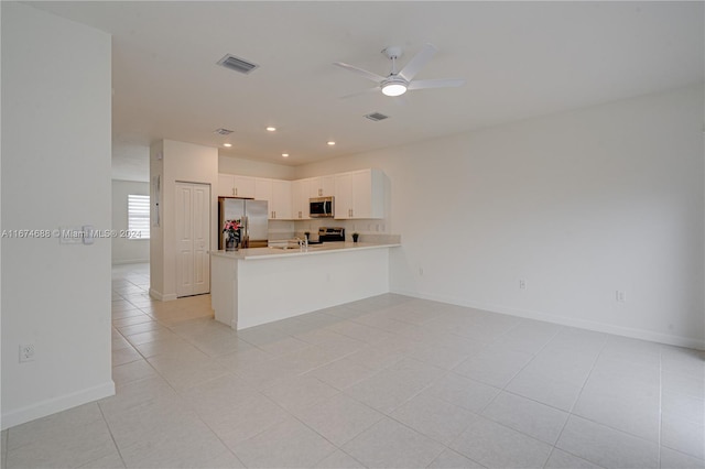 kitchen with ceiling fan, kitchen peninsula, appliances with stainless steel finishes, light tile patterned floors, and white cabinetry