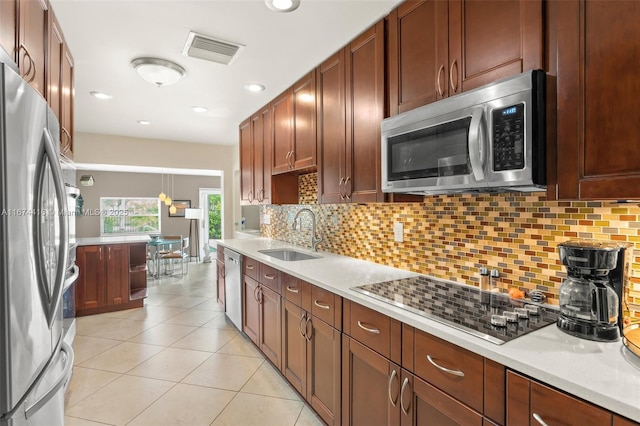 kitchen with backsplash, sink, decorative light fixtures, light tile patterned flooring, and stainless steel appliances