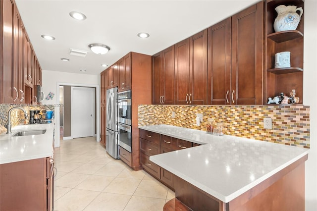 kitchen with kitchen peninsula, backsplash, stainless steel appliances, sink, and light tile patterned floors