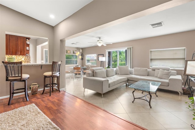 living room featuring ceiling fan, light hardwood / wood-style flooring, and lofted ceiling