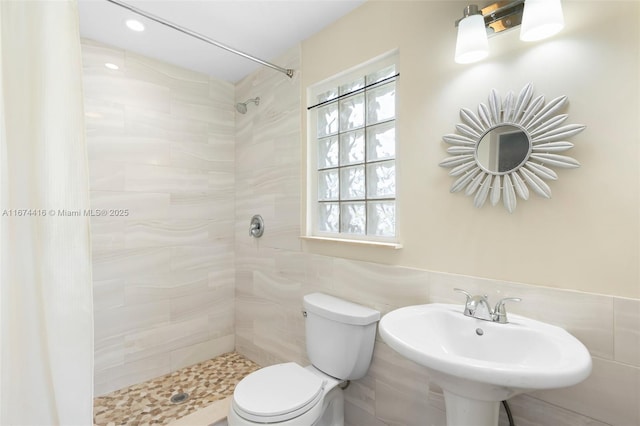 bathroom featuring a tile shower, sink, and toilet