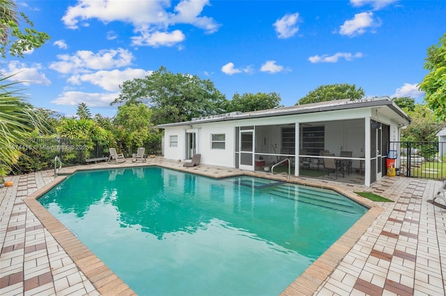 view of swimming pool featuring a sunroom and a patio area