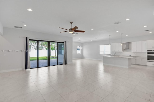 unfurnished room featuring sink, ceiling fan, light tile patterned floors, and plenty of natural light