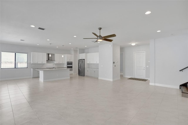 unfurnished living room featuring ceiling fan, sink, and light tile patterned floors