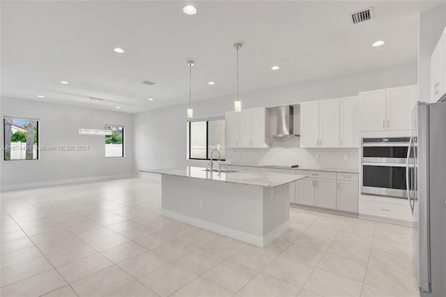 kitchen with wall chimney exhaust hood, hanging light fixtures, stainless steel appliances, and a healthy amount of sunlight