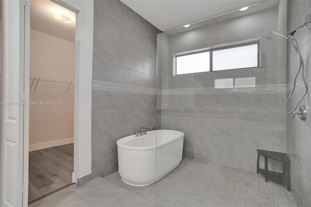 bathroom featuring hardwood / wood-style flooring, independent shower and bath, and tile walls