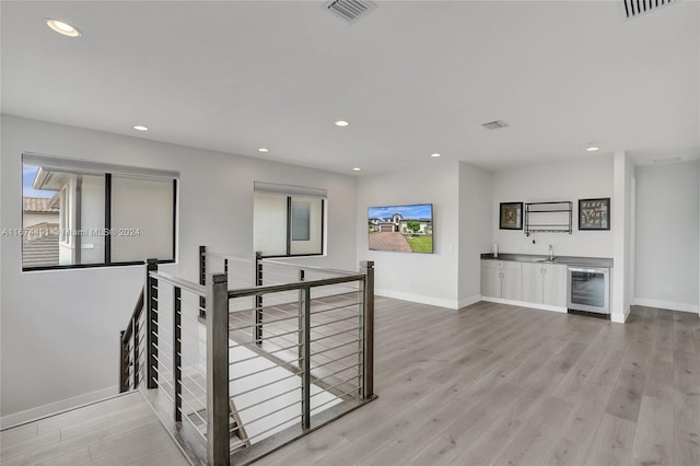 corridor with wine cooler, sink, and light hardwood / wood-style flooring