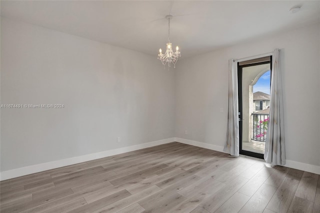 spare room with light hardwood / wood-style flooring and a notable chandelier