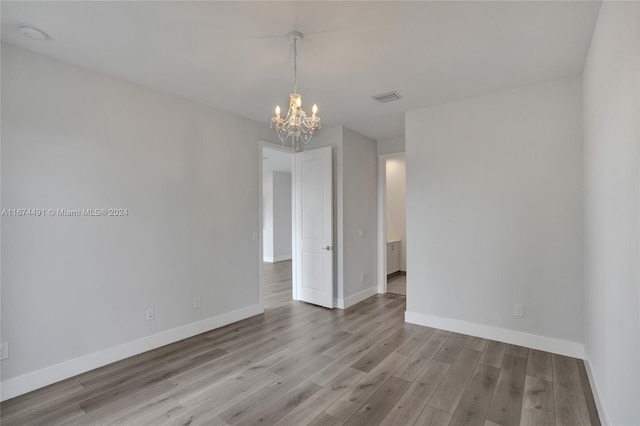 spare room with light hardwood / wood-style flooring and a chandelier