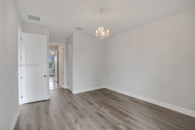 unfurnished room with an inviting chandelier and light hardwood / wood-style floors