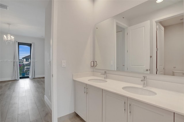 bathroom featuring an inviting chandelier, vanity, hardwood / wood-style flooring, and toilet