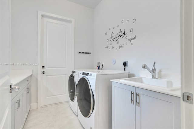 laundry room with sink, washer and dryer, light tile patterned floors, and cabinets