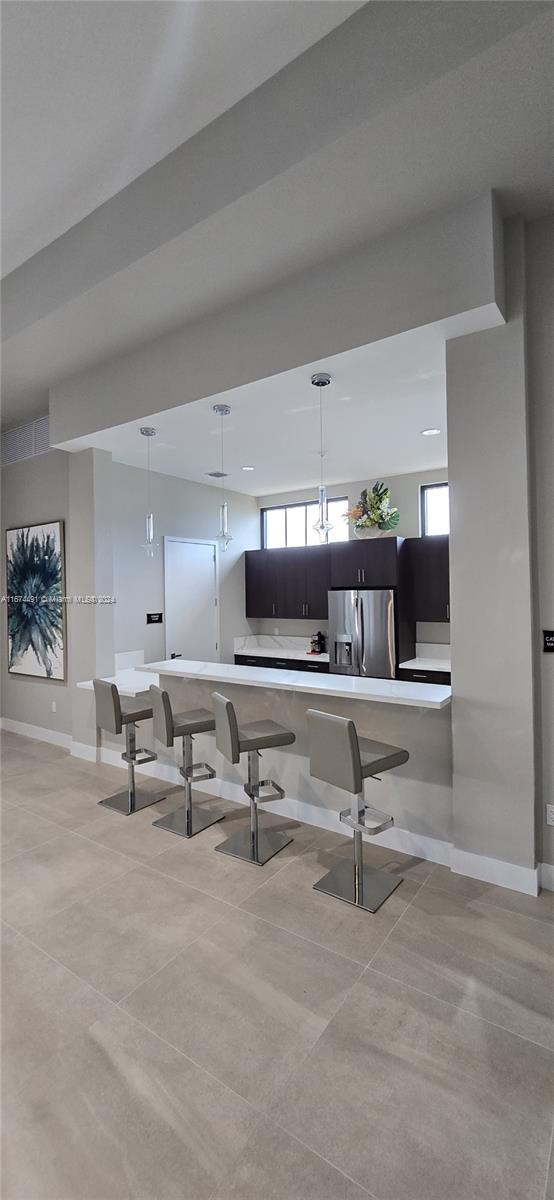 kitchen with kitchen peninsula, pendant lighting, and stainless steel fridge with ice dispenser