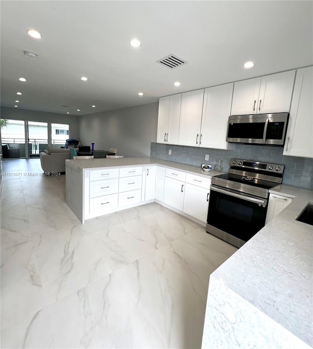 kitchen featuring light stone counters, stainless steel appliances, tasteful backsplash, kitchen peninsula, and white cabinetry