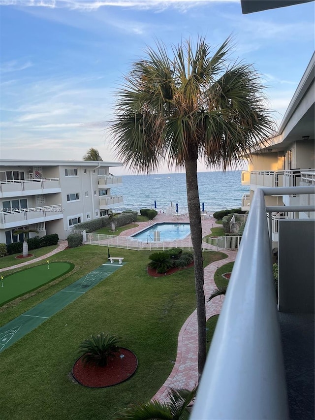 view of swimming pool with a water view and a lawn