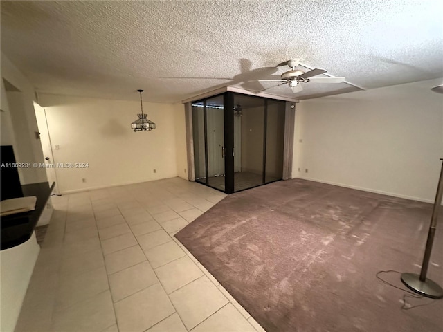 unfurnished living room with ceiling fan, light tile patterned floors, and a textured ceiling