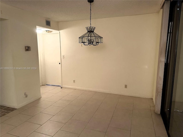 unfurnished room featuring a notable chandelier, light tile patterned floors, and a textured ceiling