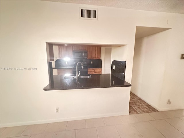 kitchen with decorative backsplash, kitchen peninsula, sink, and light tile patterned floors