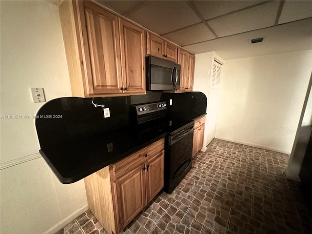 kitchen featuring black electric range oven, a kitchen bar, and a paneled ceiling