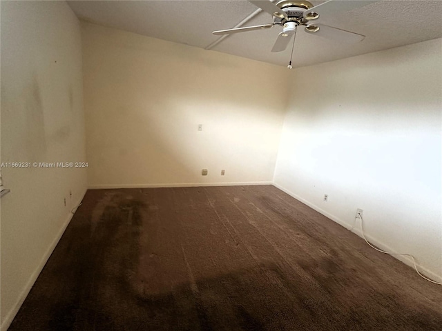 spare room featuring dark colored carpet and ceiling fan