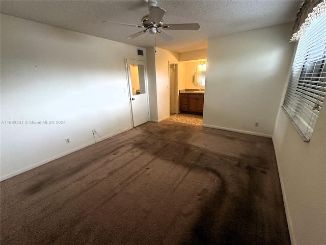 carpeted spare room featuring ceiling fan and a textured ceiling