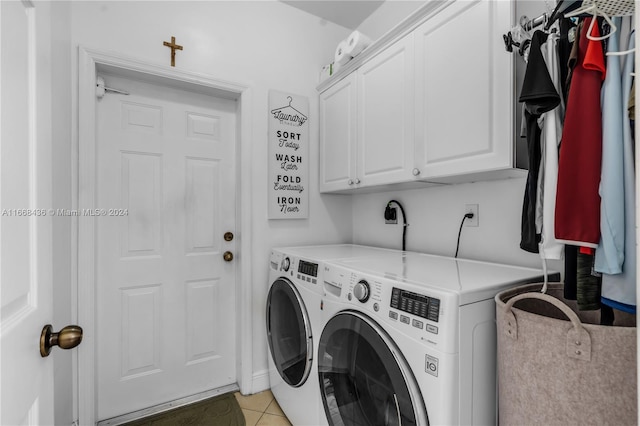 clothes washing area featuring light tile patterned flooring, washing machine and dryer, and cabinets