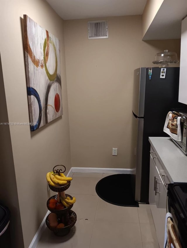 kitchen with black range with electric cooktop, stainless steel fridge, and light tile patterned floors