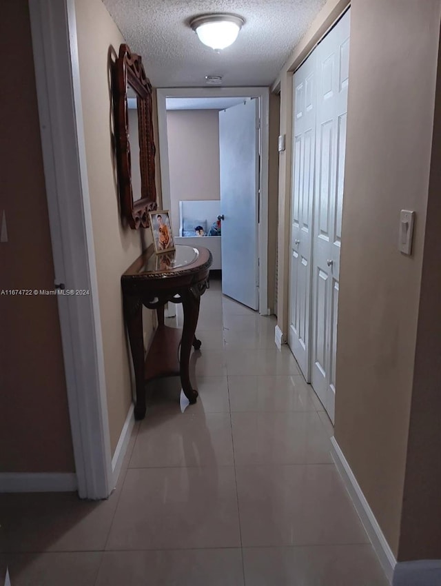 hallway featuring a textured ceiling and light tile patterned flooring