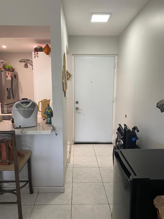 kitchen featuring kitchen peninsula, stainless steel fridge with ice dispenser, light tile patterned floors, and white cabinets