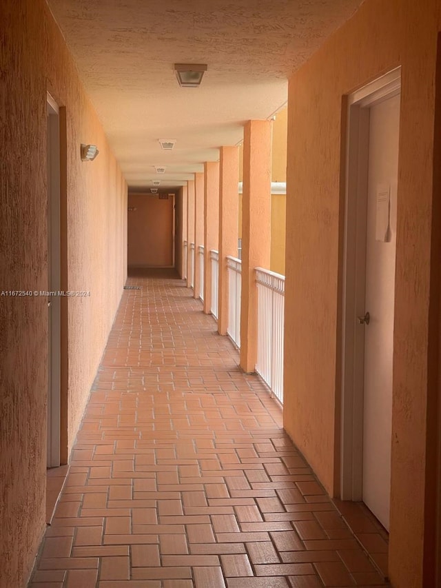 hall with a drop ceiling and light tile patterned floors