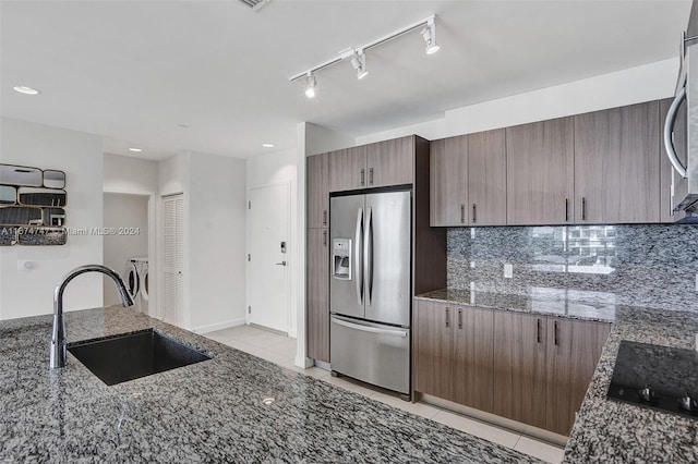 kitchen with tasteful backsplash, dark stone counters, sink, appliances with stainless steel finishes, and light tile patterned floors