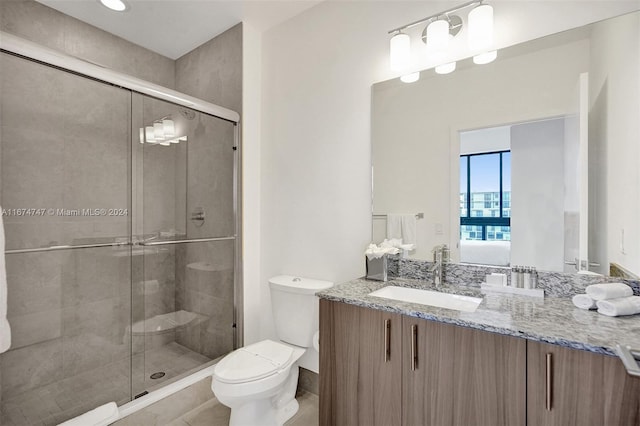 bathroom featuring a shower with door, vanity, and toilet