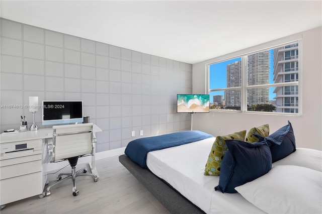 bedroom featuring light wood-type flooring and tile walls