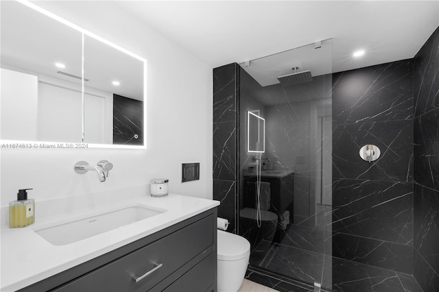 bathroom with a tile shower, vanity, and toilet