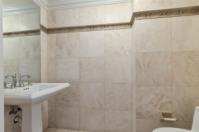 half bathroom with ornamental molding, a sink, tile walls, and toilet