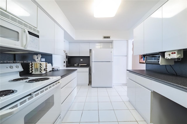 kitchen with light tile patterned floors, white cabinets, white appliances, and tasteful backsplash