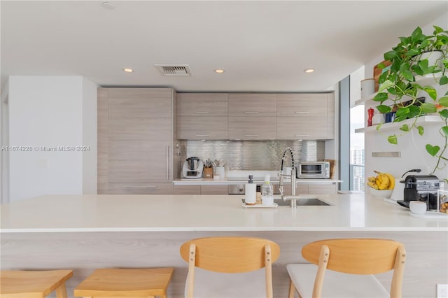 kitchen with a breakfast bar area, sink, kitchen peninsula, and tasteful backsplash