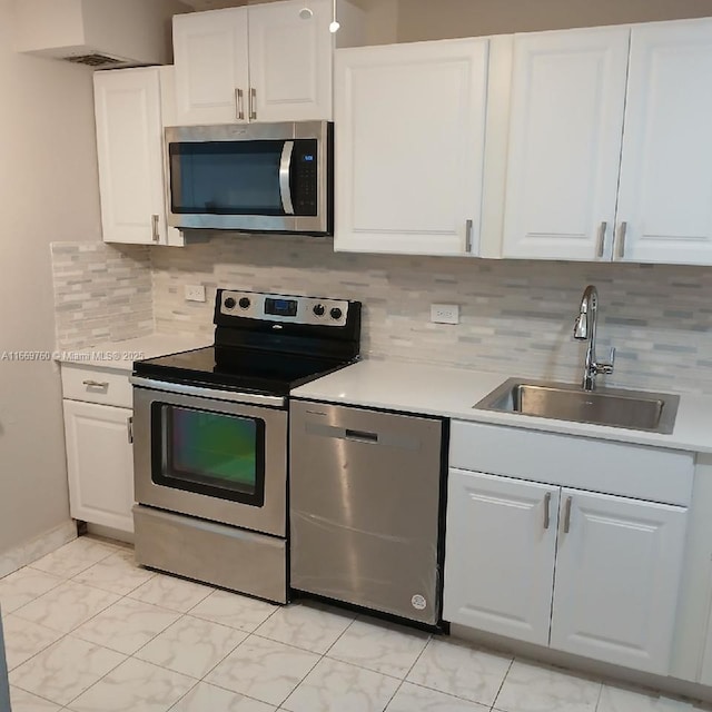 kitchen with stainless steel appliances, light countertops, a sink, and white cabinetry