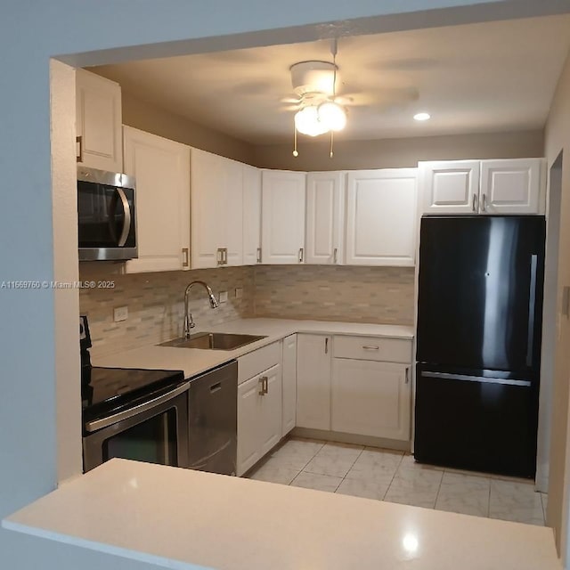 kitchen featuring a sink, white cabinets, light countertops, appliances with stainless steel finishes, and decorative backsplash