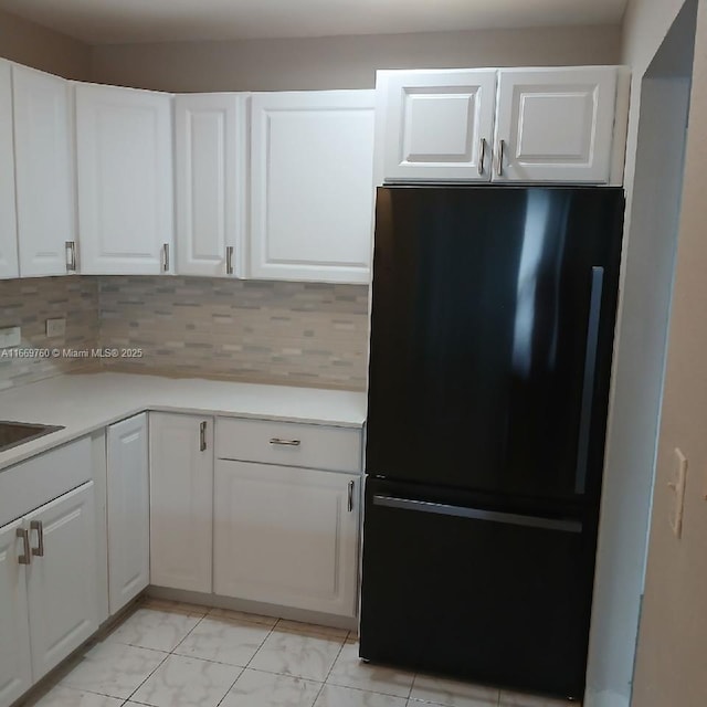 kitchen featuring white cabinets, light countertops, and freestanding refrigerator