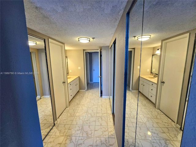 full bathroom with marble finish floor, two vanities, a sink, and baseboards