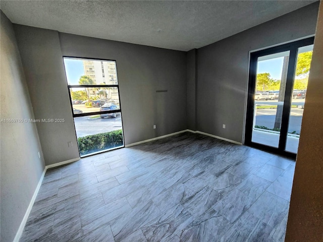 empty room featuring a textured ceiling and baseboards