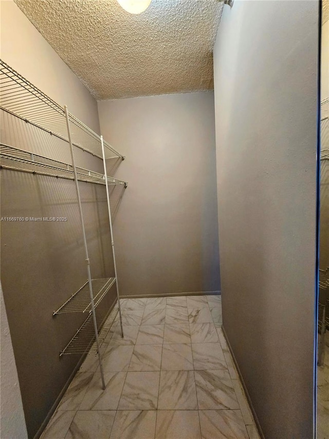 walk in closet with marble finish floor