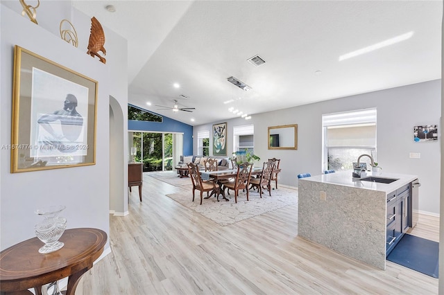 dining area with sink, ceiling fan, vaulted ceiling, and light hardwood / wood-style flooring